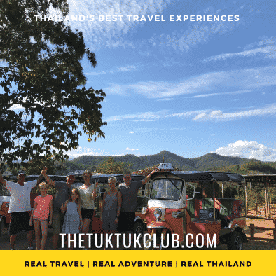 Two adults and three children smiling standing next to their bright orange Tuk Tuk in the middle of an adventure