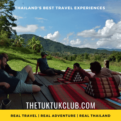 Four travellers relaxing on a raised wooden plaform at our campsite in the mountains of Northern Thailand