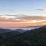 The sun setting over forested mountain in Northern Thailand with a misty valley in the distance