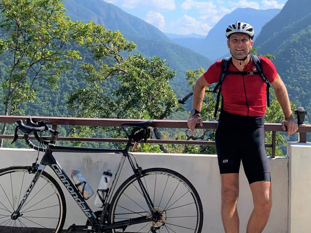 MAE HONG SON LOOP 2 A cyclist standing next to a bike with the high mountains of Mae Hong Son in the background