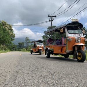 Bright orange Tuk Tuks on a small county road in Thailand