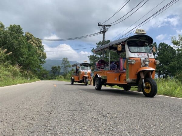 Bright orange Tuk Tuks on a small county road in Thailand