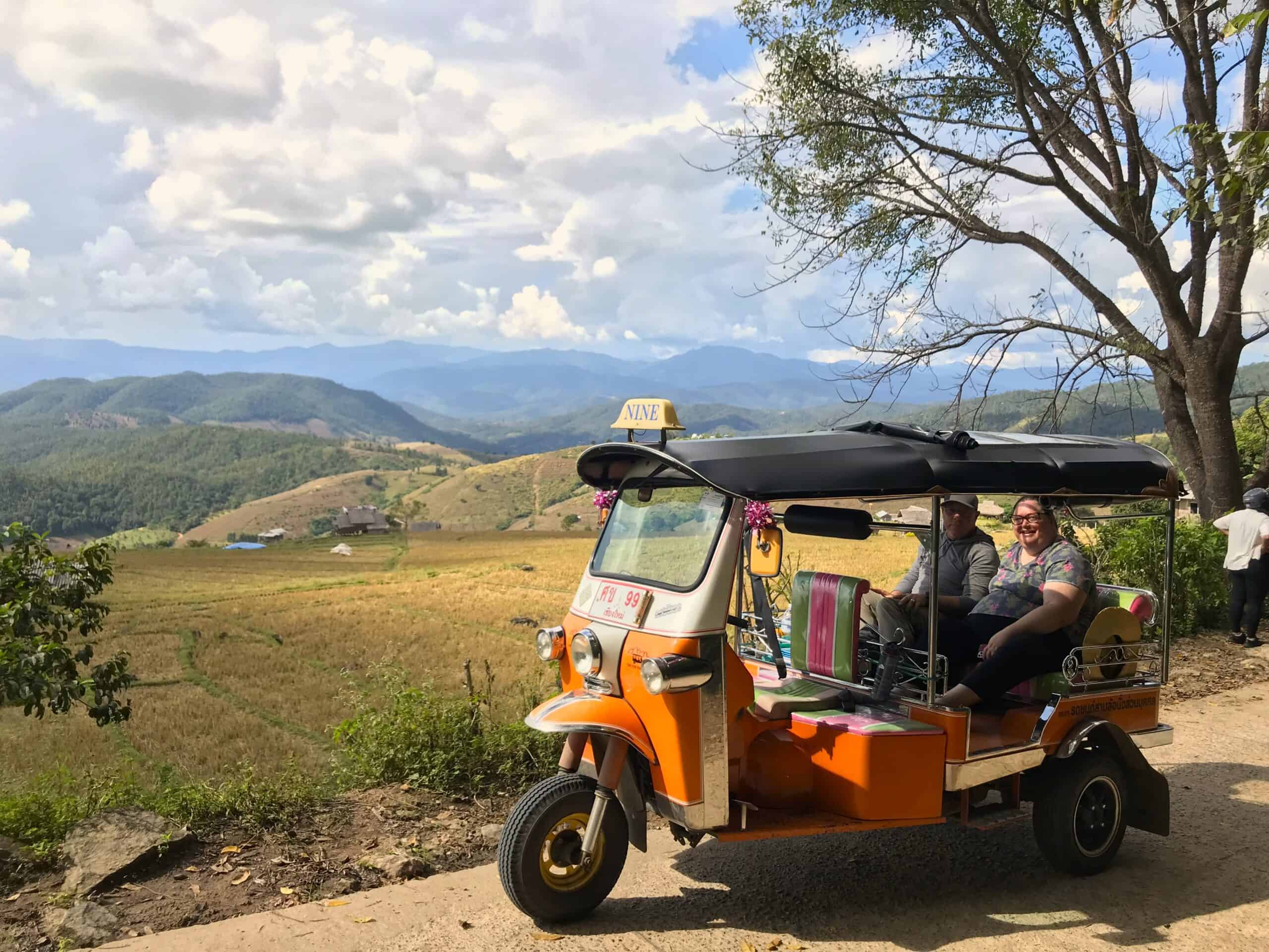 5 Day Adventure Chauffeur - Deposit 1 A Tuk Tuk on a small country road with mountains in the background