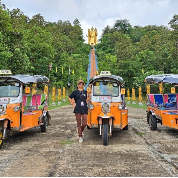 Three Tuk Tuks in front of a giant 4 Buddha image statue
