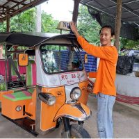 A Thai man cleaning a Tuk Tuk