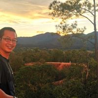 A Thai man smiling with mountains behind